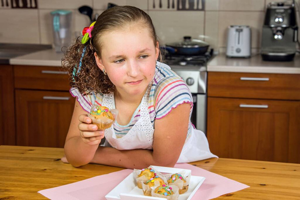 Маленькая девочка печет кексы дома, готовит завтрак или перекусить в школе - Фото, изображение
