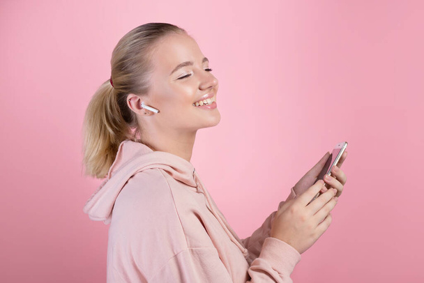 charming blonde is listening to music on wireless headphones. - Фото, изображение