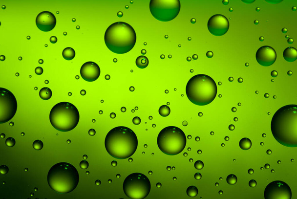 Abstract green background with water drops on the glass. A fogged beer bottle in close-up. - Foto, Imagem