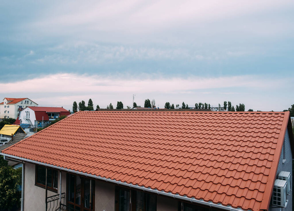 Vue sur le toit de la maison avec des carreaux de métal brun. - Photo, image