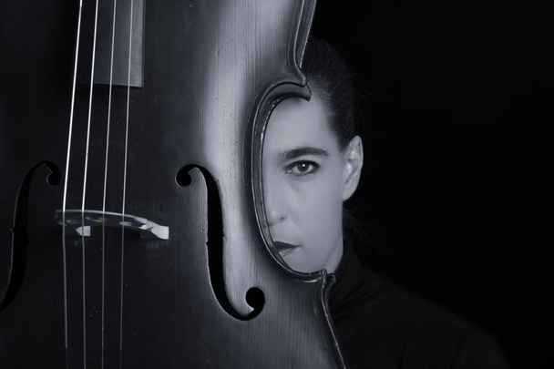 Beautiful brunette playing a cello with selective light in black - Photo, Image