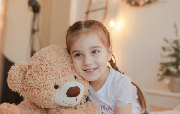 Portrait of an expressive little girl hugging her teddy bear friend - 写真・画像