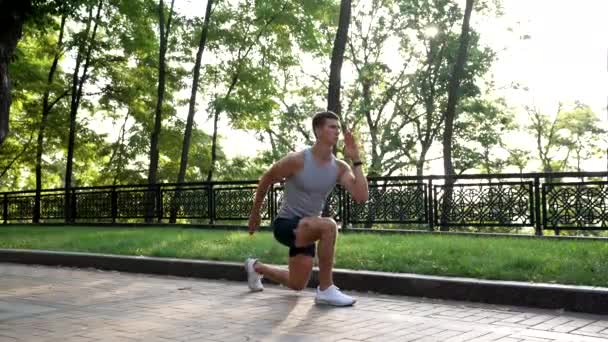 uomo muscolare che si riscalda con l'esercitazione all'aperto del affondo posteriore, addestramento - Filmati, video