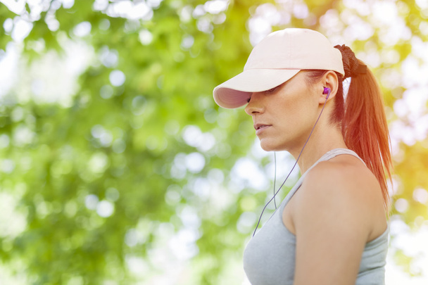 mooie jonge vrouw luisteren naar muziek tijdens sport activiteit - Foto, afbeelding