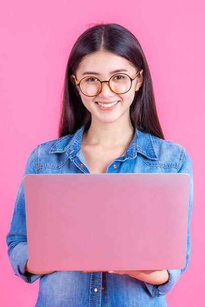 életmód gyönyörű ázsiai üzlet fiatal nő segítségével laptop számítógép online otthoni iroda elszigetelt rózsaszín háttér - online vásárlás és online banki koncepció - Fotó, kép