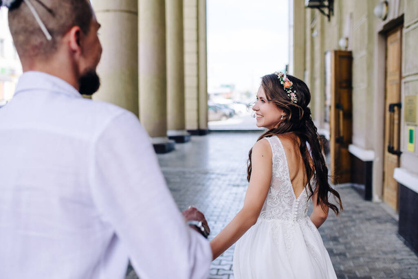 the young bride holds the groom's hand and smiles - 写真・画像