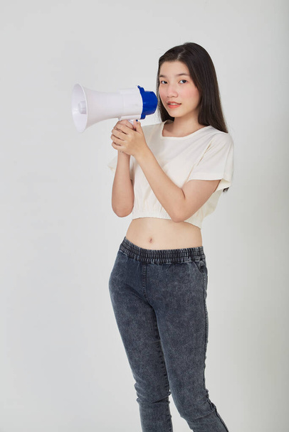 Portrait beautiful young asian woman smile with megaphone making announcement in isolated studio - 写真・画像