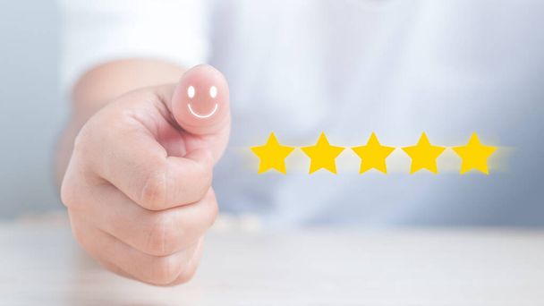 Customer hand with thumb up Positive emotion smiley face icon and five stars with copy space. Best Excellent Services Rating for Satisfaction. - Photo, Image