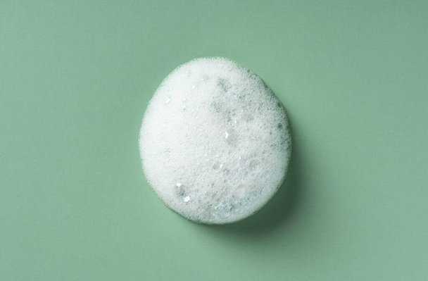 Foam texture on green background. Soap, shampoo, mousse, shower gel foam. - Foto, Imagem