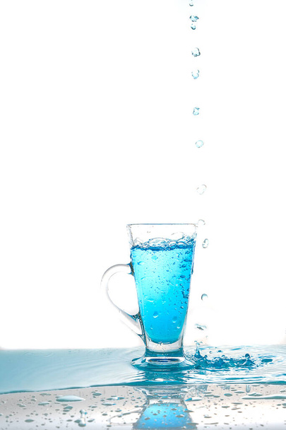 Πιτσιλιές νερού σε ποτήρι νερό σε λευκό φόντο - Φωτογραφία, εικόνα
