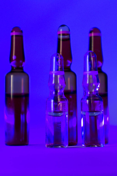 The ampoules on a purple surface in a dark room - Fotó, kép