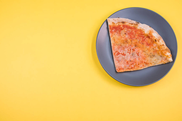 A plate with a slice of pizza isolated on a yellow background- free space for text - Φωτογραφία, εικόνα