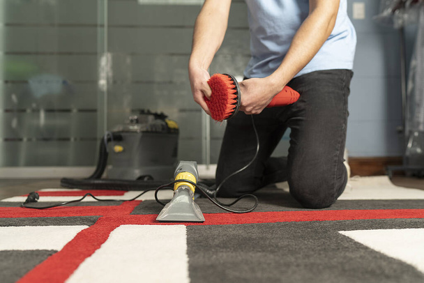 A closeup shot of a laundry worker cleaning carpet with a special electric brush - 写真・画像