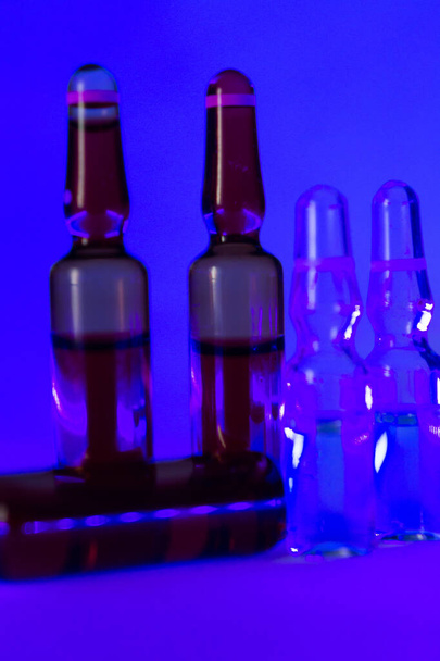 The ampoules on a purple surface in a dark room - Φωτογραφία, εικόνα