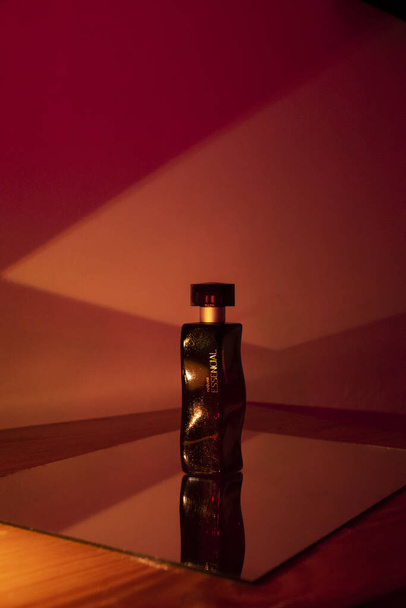 A vertical shot of a beautiful bottle of perfume captured in colorful lights - Foto, Bild
