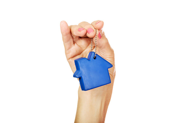 A closeup shot of a female hand holding a blue small house keychain, isolated on white - Valokuva, kuva