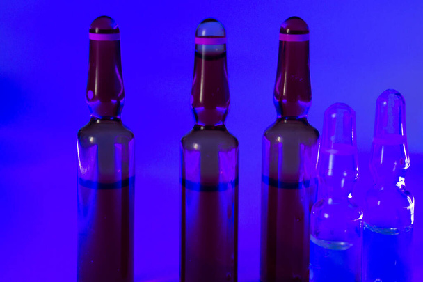 The ampoules on a purple surface in a dark room - Foto, afbeelding