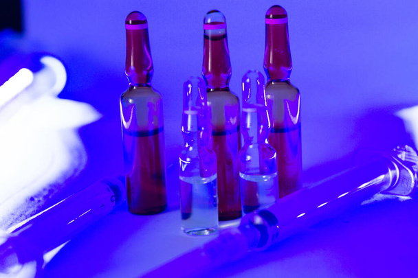 The ampoules on a purple surface in a dark room - 写真・画像