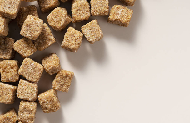 A brown cane sugar cube on a beige background with copy space. View from directly above. - Photo, image