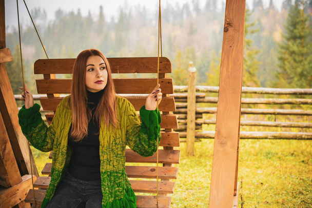 Travels concept. Woman with red hair rest in mountains and forest at cold time .Lady wear warm wool cardigan, nice fashionable casual clothes - Photo, Image
