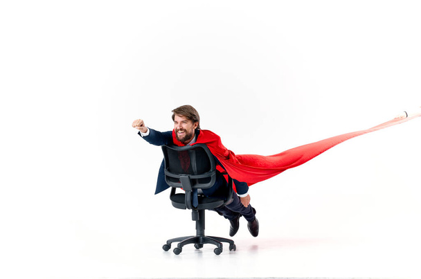obchodní muž s červeným pláštěm se snaží v superman kancelářské židle - Fotografie, Obrázek