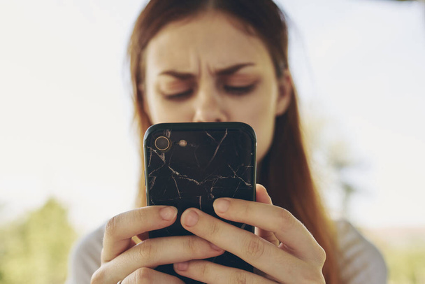 mulher ruiva com um telefone nas mãos ao ar livre - Foto, Imagem