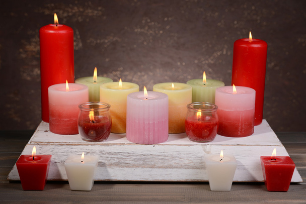 Beautiful candles with flowers on table on brown background - Foto, afbeelding