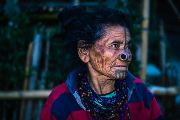 Выражение лица женщины племени апатани с ее традиционными мочками носа и размытым фоновым изображением взято в ziro arunachal pradesh india. is one of the oldest tribe of india. - Фото, изображение