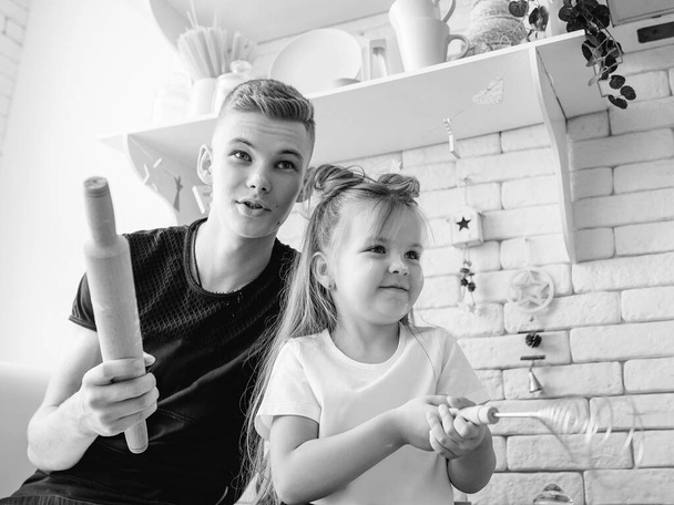 caucasian funny cute siblings in kitchen - little girl with older brother baking in kitchen. Bake, duty, fun and culinary concept - Photo, Image