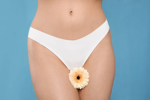 Woman in white panties with gerbera flower on light blue background, closeup - Foto, imagen