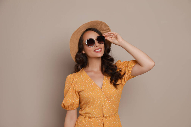 Beautiful young woman with straw hat and stylish sunglasses on beige background - Φωτογραφία, εικόνα