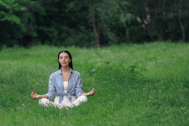 Nuori nainen meditoi vihreällä ruoholla. Tekstitila - Valokuva, kuva