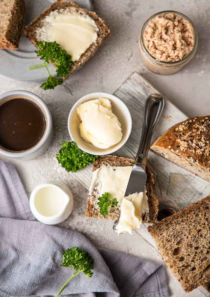 Freshly baked artisan multigrain bread with butter and pate. Breakfast with coffee, sliced bread, butter and liver pate. Light grey stone background. - Foto, Imagem