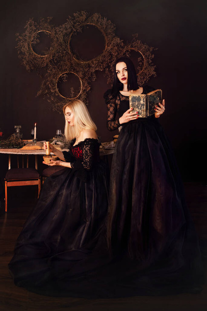 Két boszorkány csodákra képes. Egy cigány boszorkány egy varázskönyvet tart a kezében. A lányok varázsszertartást végeznek. Halloween koncepció - Fotó, kép