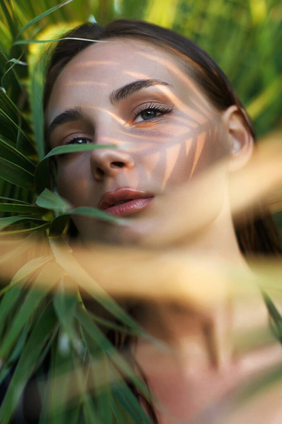 hermosa chica de verano en la puesta del sol. joven sexy mujer en hojas de palma. Primer plano Retrato de belleza - Foto, Imagen