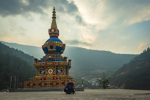 少女は仏教の仏塔の近くで瞑想していますフラットアングル画像から午前中に劇的な空とインドのアラナカル・プラデーシュ修道院で撮影されました. - 写真・画像