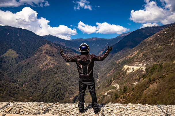 Biker in Sicherheitsausrüstung auf dem Gipfel des Berges mit strahlend blauem Himmel am Tag Bild wird am sela pass tawang arunachal pradesh indien aufgenommen. - Foto, Bild