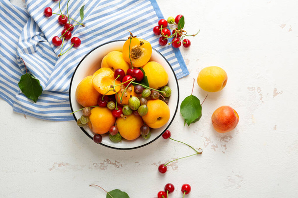 Overhead view of summer fruits in bowl on white surface - Foto, afbeelding