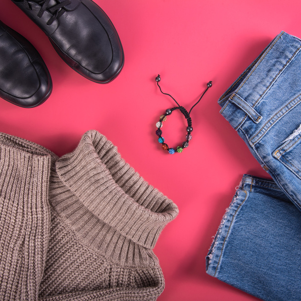 Układ damskich ubrań jesienno-wiosennych - widok z góry dżinsy, beżowy sweter i buty na różowym tle, płaski leżak - Zdjęcie, obraz