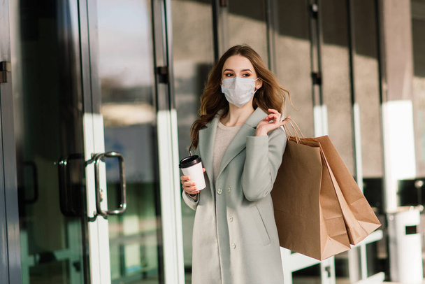 Jovem fêmea usando máscara para prevenir o vírus com sacos de compras na rua estreita na Europa. - Foto, Imagem