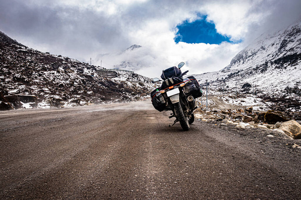 vélo chargé motard à distance route isolée avec des montagnes de calotte neigeuse à l'image de fond est prise au col de sela tawang arunachal pradesh. - Photo, image