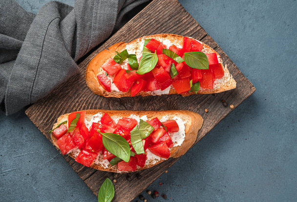Fried toast with tomatoes, feta, and basil close-up. Traditional Italian appetizer, bruschetta with tomatoes. - Fotoğraf, Görsel