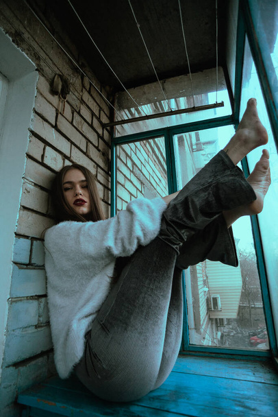 Menina sexy bonita posando na varanda. Retrato de foto de arte de uma menina em um estilo moderno com um sentado e acrescentou ruído na foto. - Foto, Imagem