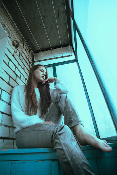 Schöne junge sexy Mädchen posiert auf dem Balkon. Kunst Fotoporträt eines Mädchens in einem modernen Stil mit einer sitzenden und zusätzlichen Lärm auf dem Foto. - Foto, Bild