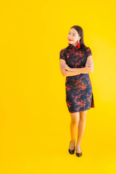 Portrét krásná mladá asijská žena nosit čínské šaty s akcí pro čínský nový rok koncept na žlutém izolovaném pozadí - Fotografie, Obrázek