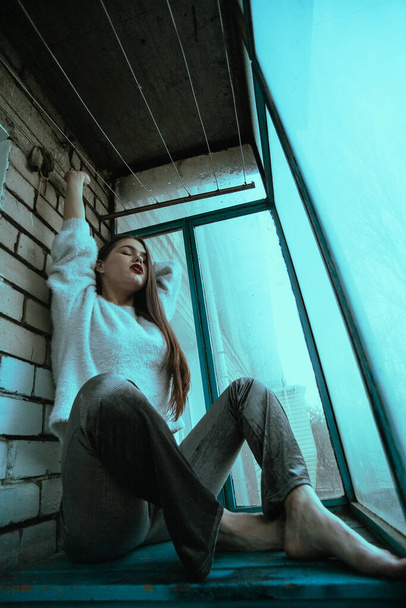 Menina sexy bonita posando na varanda. Retrato de foto de arte de uma menina em um estilo moderno com um sentado e acrescentou ruído na foto. - Foto, Imagem