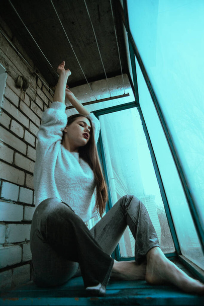 Красива молода сексуальна дівчина позує на балконі. Художній фотопортрет дівчини в сучасному стилі з сидячим і доданим шумом на фото
. - Фото, зображення