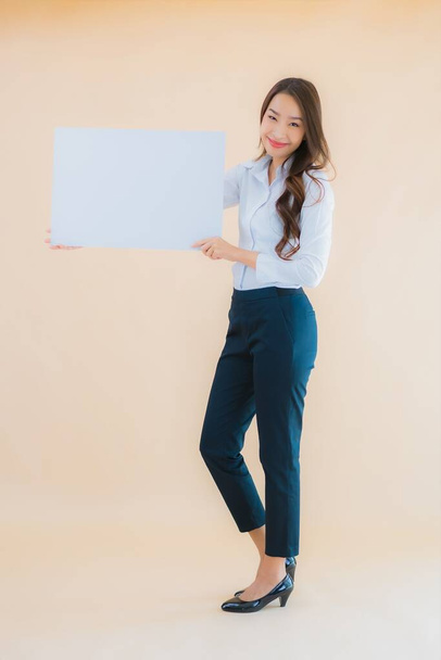 Retrato hermosa joven asiática mujer de negocios mostrar blanco cartelera vacía en fondo de color aislado - Foto, Imagen
