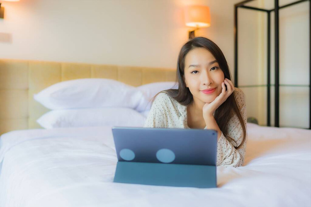 Güzel bir Asyalı kadının portresi yatak odasının içinde kredi kartıyla tablet kullanıyor. - Fotoğraf, Görsel
