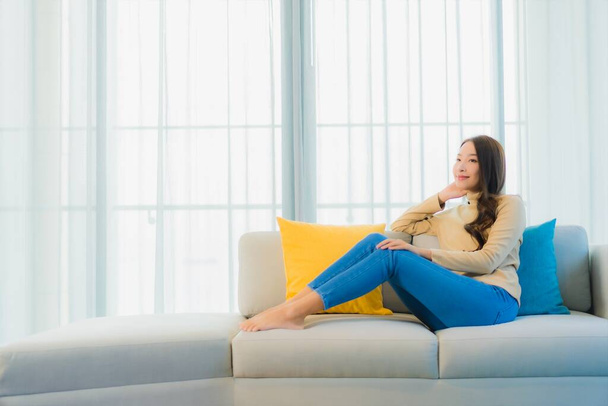 Muotokuva kaunis nuori aasialainen nainen rentoutua vapaa nauttia sohvalla olohuoneessa sisustus - Valokuva, kuva